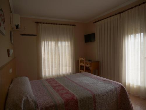 a bedroom with a bed and two windows at Hostal Durá in Torrellano