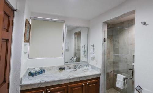a white bathroom with a sink and a shower at Condominios Ballena in Cabo San Lucas