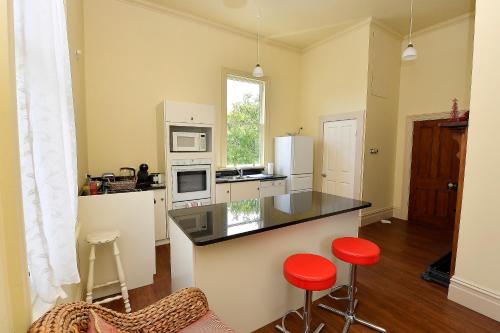 a kitchen with a counter and two red bar stools at Harold House in Reefton