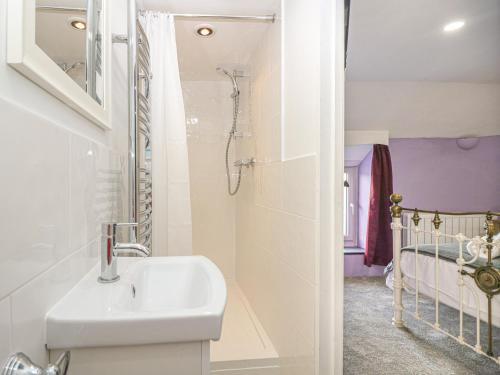 a bathroom with a sink and a shower and a crib at Pebble Cottage in Redruth