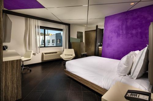 Habitación de hotel con cama y paredes moradas en The Moment Hotel, en Los Ángeles