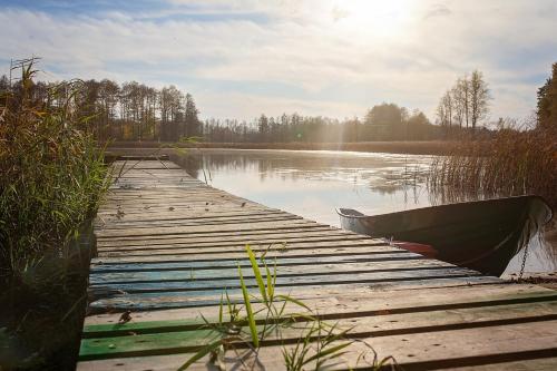 a boat is parked next to a dock on a lake at Maly Domek Zalesie in Barczewo