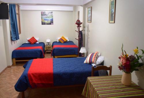 a hotel room with two beds with colorful blankets at Pumamarka House in Ollantaytambo