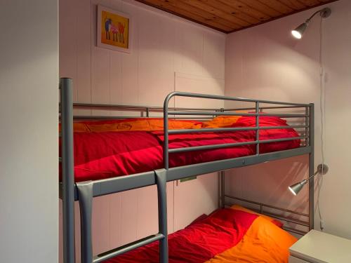2 Etagenbetten in einem Zimmer mit roter und orangefarbener Bettwäsche in der Unterkunft Clos des Chevreuils - Le Chalet in Barbençon