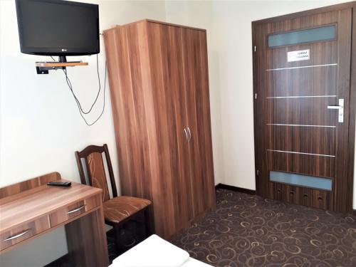 um quarto com um armário de madeira e uma televisão em Motel Orion Wolsztyn em Wolsztyn