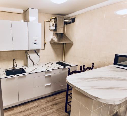 a kitchen with white cabinets and a table at Kaunas Castle Apartments - 2 Bedroom Flat in Kaunas