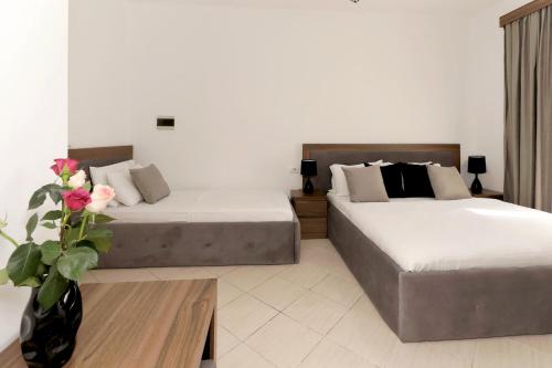 two beds in a hotel room with a vase of flowers at Villa Doka in Sarandë