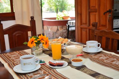 a table with cups and plates of food and drinks at Nuevas Cabañas Del Sol in San Lorenzo