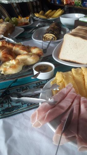 a table topped with plates of food and a person holding a spoon at Nuevas Cabañas Del Sol in San Lorenzo