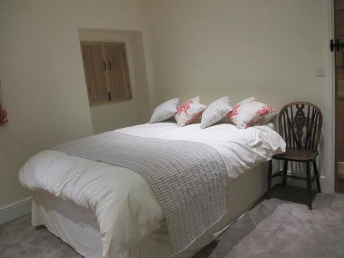 una camera da letto con letto, lenzuola e cuscini bianchi di Lavender Cottage a Holmesfield