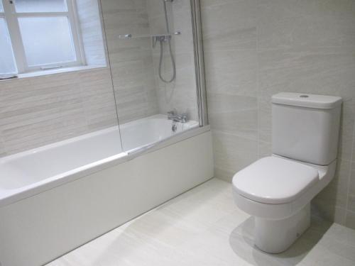 a white bathroom with a toilet and a shower at Lavender Cottage in Holmesfield