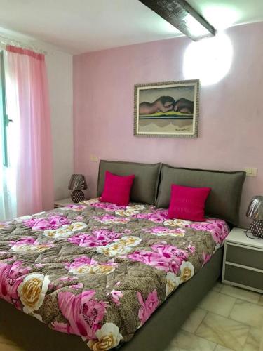 ラ・スペツィアにあるAppartamento Il Soleのピンクの壁のベッドルーム1室(大型ベッド1台付)