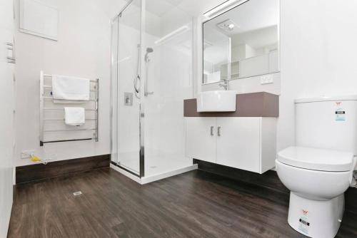a white bathroom with a toilet and a shower at Port Central No 2 in Port Campbell