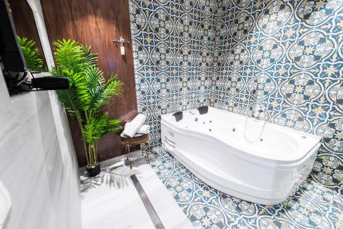 a bathroom with a tub and blue and white tiles at צימר בוטיק אדלה Zimmer boutique adela in Arad
