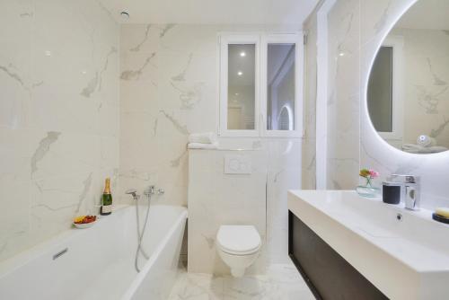 La salle de bains blanche est pourvue d'une baignoire, de toilettes et d'un lavabo. dans l'établissement BASTILLE/LE MARAIS-LUXURIOUS 3 rooms flat, à Paris