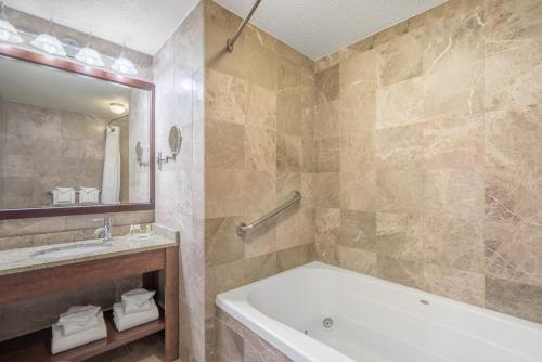 a bathroom with a tub and a sink and a mirror at Holiday Inn Cape Cod - Hyannis by IHG in Hyannis
