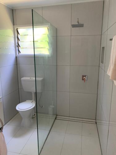 a bathroom with a toilet and a glass shower at Kura's Kabanas in Rarotonga