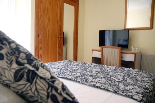 a bedroom with a bed with a blue and white blanket at Hotel Playa de Merón in San Vicente de la Barquera