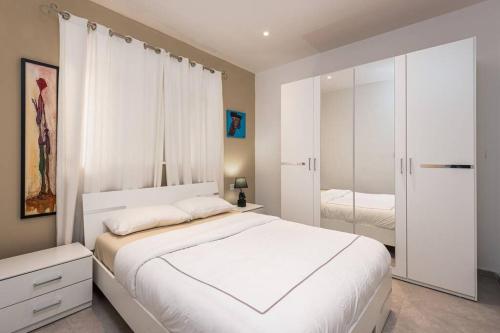 1 dormitorio con 1 cama blanca grande y espejo en Sliema Smart SeaView Apartment, en Sliema