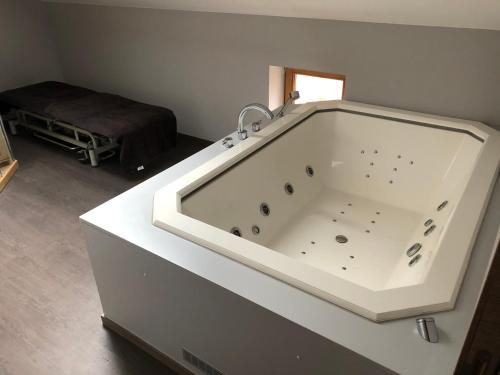 a large white bath tub in a room with a bed at Cosy Welness Seneffe in Seneffe