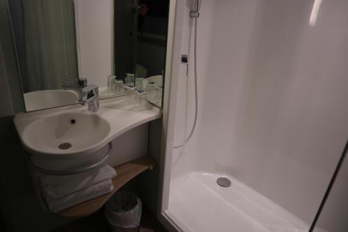 a white bathroom with a sink and a shower at ibis Budget Le Treport Mers Les Bains in Mers-les-Bains