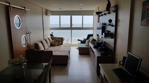a living room with a couch and a view of the ocean at A melhor vista de Santos para 5 pessoas pé na areia in Santos