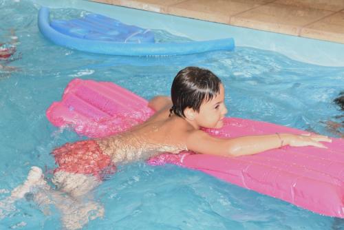 a young boy is laying in a pool of water at Altair Hotel in San Clemente del Tuyú