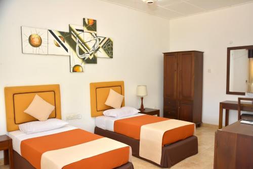 a hotel room with two beds and a desk at Yolanda Villa Negombo in Negombo
