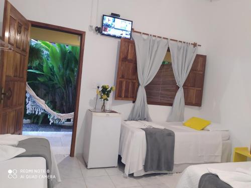 a bedroom with two beds and a tv on the wall at Pousada João Maria in Trancoso