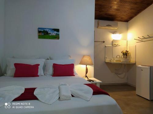 a bedroom with a large white bed with red pillows at Pousada João Maria in Trancoso