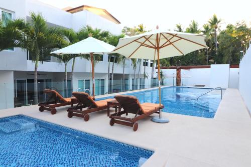 uma piscina com cadeiras e um guarda-sol ao lado de uma piscina em LYDMAR BOUTIQUE HOTEL em Zihuatanejo