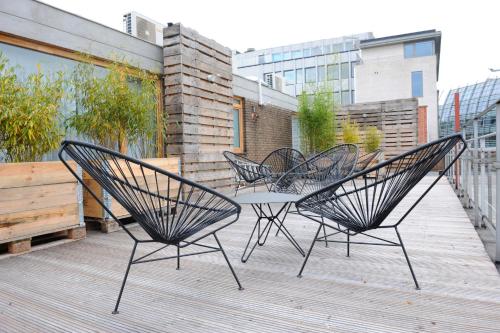 three chairs and a table on a deck at 9Hotel Chelton in Brussels