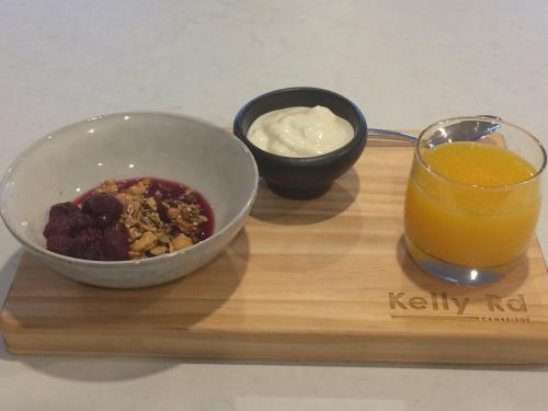 a bowl of cereal and a glass of orange juice on a wooden tray at Kelly Rd Cambridge Lodge in Cambridge