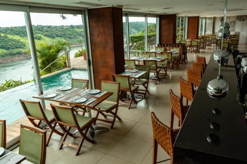 a restaurant with tables and chairs and a view of the water at Hotel Guaminí Misión in Puerto Iguazú