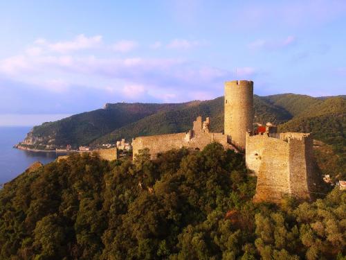 a castle on top of a hill next to the water at La vita è bella - Noli in Noli