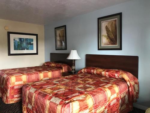 a hotel room with two beds and a lamp at Immokalee Inn in Immokalee
