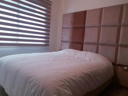 a bedroom with a white bed and a window at MAARIF LUXURY APART -Urban Massira IV- in Casablanca