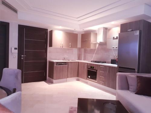 a large kitchen with wooden cabinets and a refrigerator at MAARIF LUXURY APART -Urban Massira IV- in Casablanca