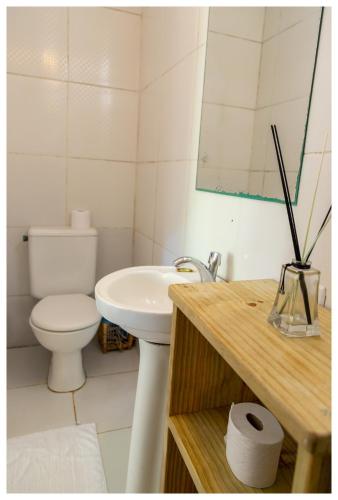 a white bathroom with a toilet and a sink at Pousada Mar Azul in Trancoso