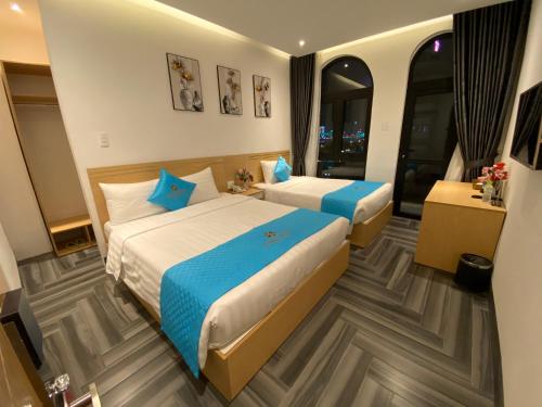 two beds in a hotel room with blue pillows at Euro Star Riverside Hotel in Da Nang