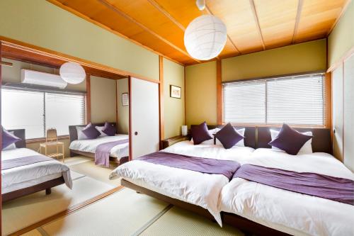 a bedroom with two beds and two windows at Chikyuutabikazoku USJ Ⅱ in Osaka