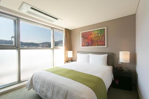 a bedroom with a large bed with a large window at Aventree Hotel Busan in Busan