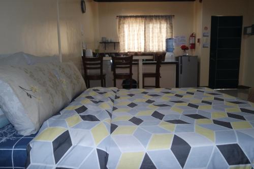 a bedroom with a large bed and a kitchen at Yoo C Apartment in Dumaguete