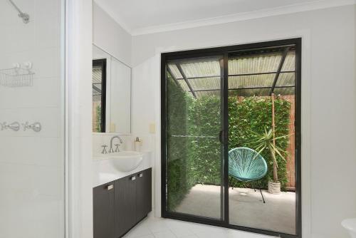 a bathroom with a sink and a sliding glass door at Tree Top Oasis in Buderim