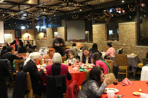 a group of people sitting at tables in a restaurant at Brickyard Retreat at Mutianyu Great Wall Adjoin to Mutianyu Great Wall - Room with the View of Great Wall - Chinese massage experience - Vehicle Shuttle Service - International Catering - SPA& Nail Beauty Facilities in Huairou