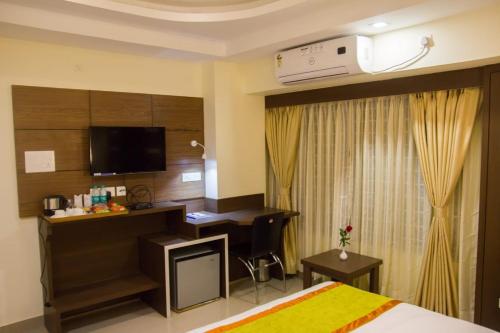 a hotel room with a bed and a desk with a computer at Hotel Park Riviera in Guwahati