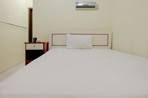 a bedroom with a white bed with a pillow on it at Zulfina Homestay Syariah Mitra RedDoorz in Banyuwangi