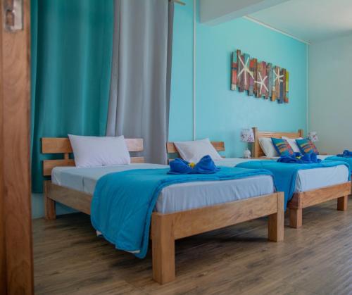 two beds in a room with blue walls at Villa Paradise Rodrigues in Rodrigues Island