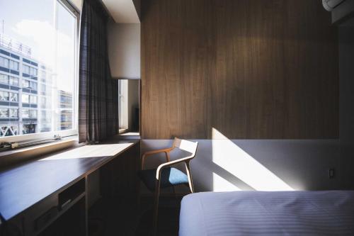 a bedroom with a bed and a desk and a window at Hotel Kajiwara in Matsuyama
