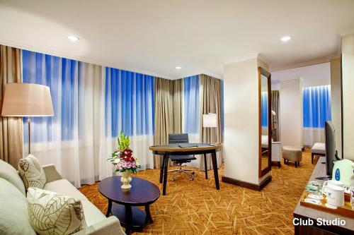a hotel room with a couch and a table at Menara Peninsula Hotel in Jakarta